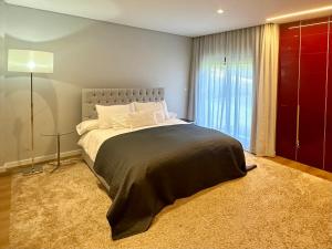 a bedroom with a large bed and a window at BelArt Luxury Golf Villa in Aroeira