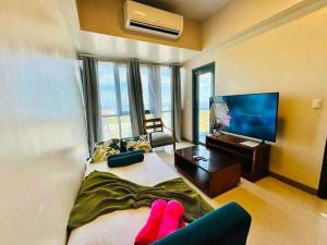 a bedroom with a bed with a television and pink socks at Mactan Newtown By The Beach in Lapu Lapu City