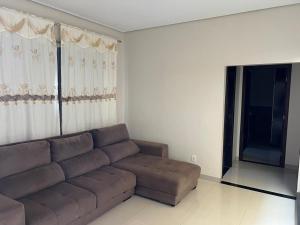 uma sala de estar com um sofá castanho e uma janela em Casa Mobiliada Itaubas com ar condicionado em Sinop
