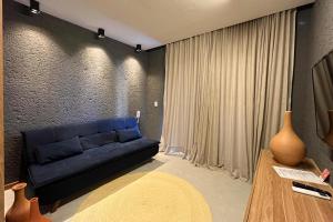 uma sala de estar com um sofá azul e uma mesa em Flat Villas Manatee Patacho em Porto de Pedras