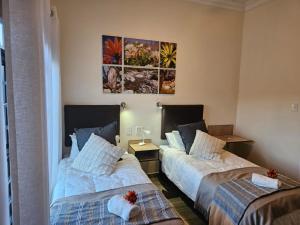 a bedroom with two beds and a painting on the wall at Oorlogs Kloof Mountain Retreat Montagu in Montagu