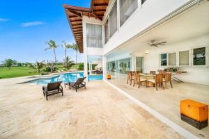 - patio ze stołem i krzesłami oraz basenem w obiekcie Casa de Campo Elegance - 8-Bedroom Golf View Villa w mieście La Romana