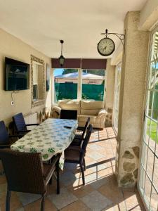 una sala da pranzo con tavolo, sedie e orologio di Chalet con piscina El Refugio de Venecia a El Campillo