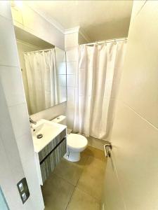 a white bathroom with a toilet and a sink at Jardines del Pacífico 3 in La Serena