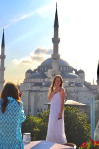 Eine Frau in einem weißen Kleid, die vor einem Gebäude steht. in der Unterkunft Blue House Hotel Old City - Sultanahmet in Istanbul