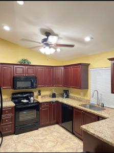 een keuken met houten kasten en een plafondventilator bij Sunshine Home in Cape Coral