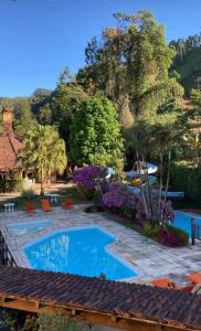 una piscina en un patio con árboles y flores púrpuras en Alugamos para grupos, en Vargem Alta