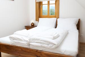 a bed with white sheets and a window at Koliba Hubertka in Oravice
