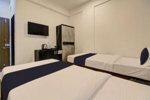 een hotelkamer met 2 bedden en een televisie bij Grey House in Pune