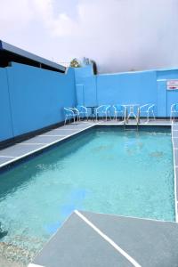 a swimming pool with chairs next to a building at Caribbean Tourist Villa in Port-of-Spain