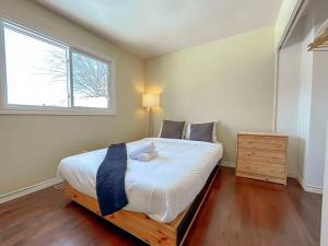 a bedroom with a bed with white sheets and a window at Spacious 5BR home. Close to everything! in Gatineau