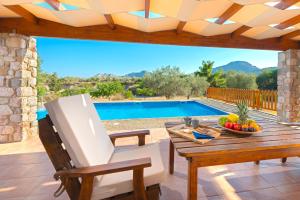 a patio with a table and a chair and a pool at Olive Private Villa up to 12 in Kolymbia