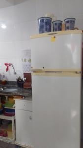 einen weißen Kühlschrank in einer Küche mit Geschirr darüber in der Unterkunft Suítes Queen Central in Uberaba