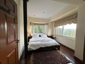 a bedroom with a bed and a large window at Sarah's Lodge in Murree