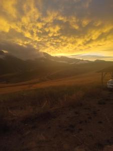 a sunset in the desert with a car parked in a field at Pampachayoq - Mountain retreat in Urubamba
