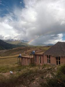 a rainbow over a house in a field at Pampachayoq - Mountain retreat in Urubamba +60 photos