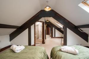 a attic with two beds in a room with beams at Madison House - Converted Church 5 Bed Pontypool in Pontypool