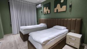 Calipso Dushanbe Hotel في دوسهانبي: سريرين توأم في غرفة بجدران خضراء