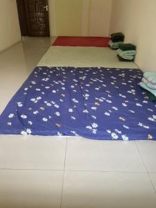 Una cama con una manta azul con flores blancas. en nhà hưng hà, en Dien Bien Phu