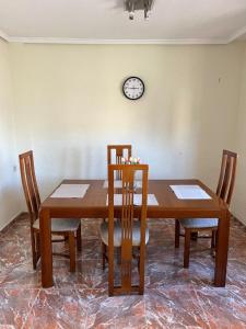 a dining room table with chairs and a clock on the wall at Piso Completo cerca de Artes Y Ciencias in Valencia