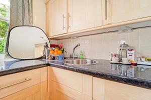 a kitchen with a sink and a mirror on the counter at Park Views Apartments in Teddington