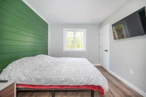 um quarto com uma cama com uma parede verde em Riverside Retreat: Maazah Cottage em Fort Coulonge