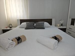 ein weißes Bett mit zwei Handtüchern und Kissen darauf in der Unterkunft Blanca in Kaštela