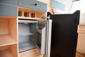 an empty refrigerator in a kitchen with its door open at Sleep Space 24 - Green Tiny Spot Schillig in Wangerland
