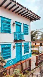 un edificio con ventanas azules y una valla en Villa Linda ApartaHotel en Jericó