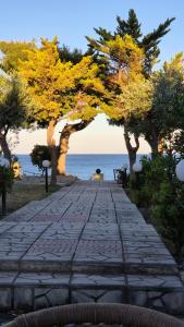 a stone path with trees and the ocean in the background at Silis House on the beach in Artemida