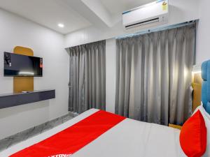 a bedroom with a red and white bed and a window at OYO 82103 Hotel Galaxy in Surat
