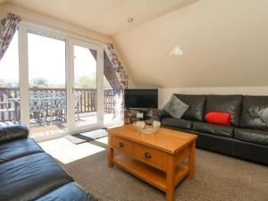 a living room with a black leather couch and a table at Honeycombe Lodge in Callington