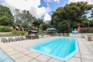 a large swimming pool with chairs and a table at Honeycombe Lodge in Callington