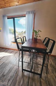 mesa y sillas en una habitación con ventana en Alquiler Turistico Los Notros en Dina Huapi