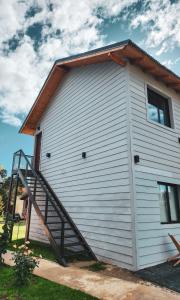 Una casa blanca con una escalera en el lateral. en Alquiler Turistico Los Notros en Dina Huapi
