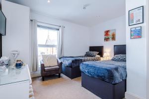 a bedroom with two beds and a chair and a window at Contractor Accommodation Barnetby in Barnetby le Wold