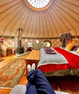a person laying on a bed in a yurt at Stamford Meadows Glamping with Private Hot Tubs in Stamford
