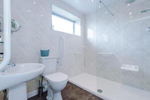 Baño blanco con aseo y lavamanos en Holcombe Guest House en Barnetby le Wold