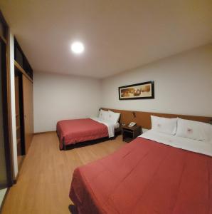 um quarto de hotel com duas camas e um cobertor vermelho em My Rouse Hotel em Chiclayo