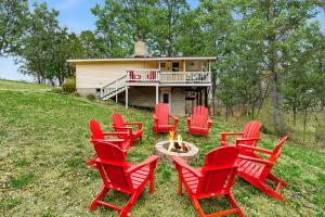 a group of red chairs around a fire pit in front of a house at Harpers Ferry Cabin w Hot Tub, Huge Deck, Firepit, & WiFi! in Harpers Ferry