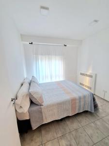 Cama en habitación blanca con ventana en Le Bleu Apartamento en Buenos Aires