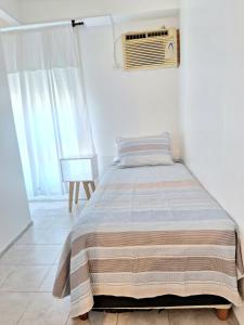 a bed with a striped blanket in a bedroom at Le Bleu Apartamento in Buenos Aires