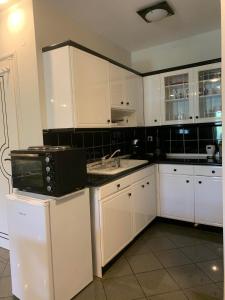 a kitchen with white cabinets and a black microwave at Eden Garden Villa in Skalánion