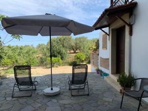 un patio con 2 sillas y una sombrilla en Eden Garden Villa en Skalánion
