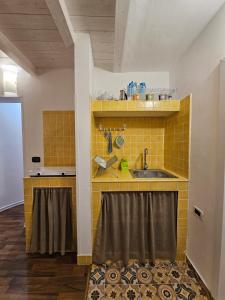 een keuken met een wastafel en een gele tegelwand bij La Casetta di Vale in Taranto