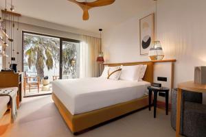 a bedroom with a large white bed and a balcony at Alai Crete a Tribute Portfolio Resort in Stalida