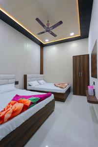 a bedroom with two beds and a ceiling fan at Shiv Residency in Mathura