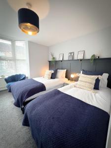 drie bedden in een kamer met blauw en wit bij Campbells Crib in Kent