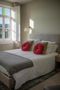 1 dormitorio con 1 cama grande y 2 almohadas rojas en Costeira Douro, en Castelo de Paiva