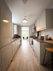 uma cozinha com armários brancos e piso em madeira em Campbells Crib em Kent